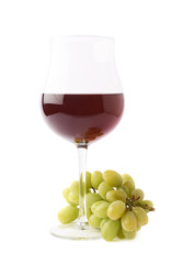 Glass of red wine next to a branch of grapes