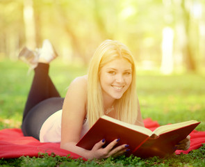 Fototapeta premium Beautiful smiling woman reading book in park
