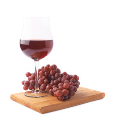 Glass of red wine next to a branch of grapes