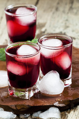 Red berry juice with ice in the shape of hearts, selective focus
