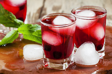 Red berry juice with ice in the shape of hearts, selective focus