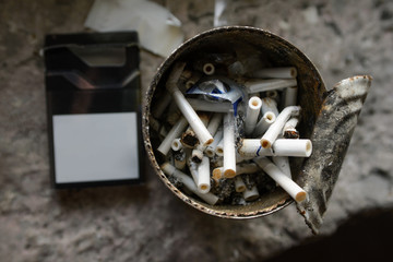 Cigarette ash and butts in a dirty tin.