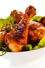 Grilled chicken legs and vegetables on white background 