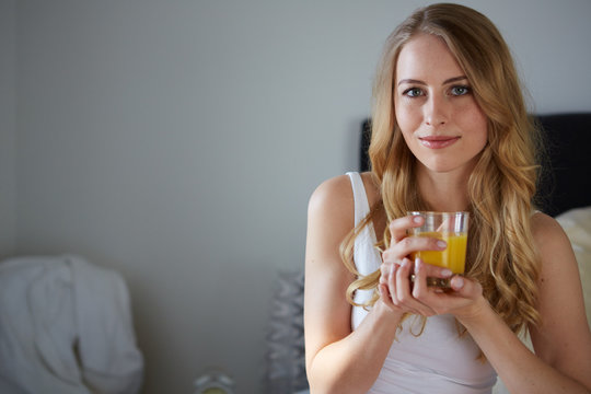 junge frau trinkt saft im bett
