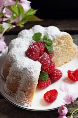 Vanilla cake with fresh raspberries on a rustic dark background 