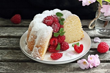 Vanilla cake with fresh raspberries on a rustic dark background 