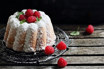 Vanilla cake with fresh raspberries on a rustic dark background 