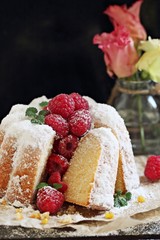 Vanilla cake with fresh raspberries on a rustic dark background 