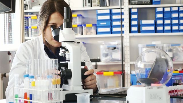 technician in the laboratory using a microscope