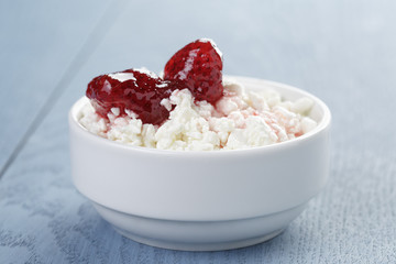 cottage cheese with strawberry jam in white bowl on blue wooden