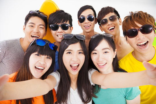 group of smiling friends with camera  taking selfie