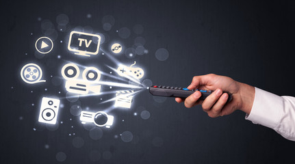 Hand with remote control and media icons