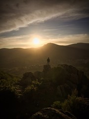 Fototapeta premium Hombre en lo alto de la montaña contempla la puesta de sol 2