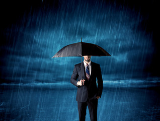 Business man standing in rain with an umbrella