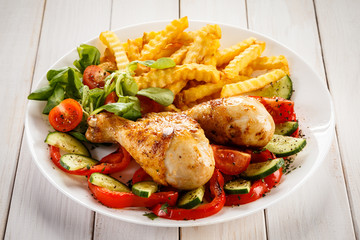 Grilled chicken drumsticks with chips and vegetables 
