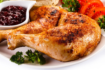Grilled chicken legs and vegetables on white background