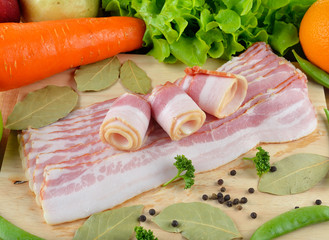 Sliced Bacon with herbs on the wooden bckground
