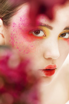 Girl closeup beauty portrait with blurred red flowers