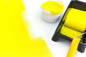 can of yellow paint with paint roller and tray