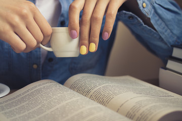 Girl in a denim shirt sits at the table and reading a book