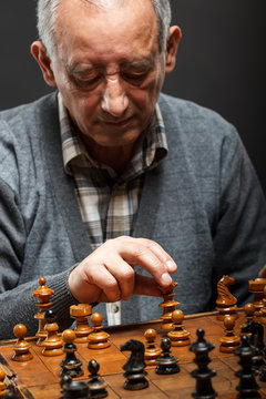 Portrait of senior man playing chess, isolated.