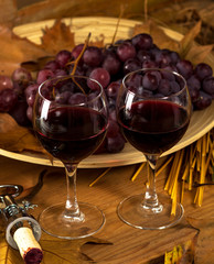Two glasses of red wine with grapes.