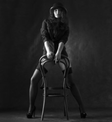 Sexy woman in black stockings and hat is dancing .
