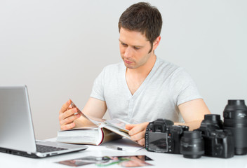 Male photographer watching photo album at his workplace.