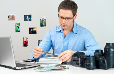Male photographer watching photo album at his workplace.