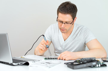 Male technician soldering lan switch router at his workplace.