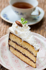 Piece of cake with vanilla frosting and a cup of tea
