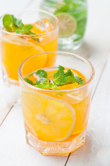 Orange juice in glass with mint, fresh fruits on wooden backgrou