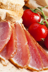 Pork smoked ham and tomatoes on the board, selective focus