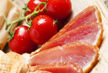 Pork smoked ham and tomatoes on the board, selective focus