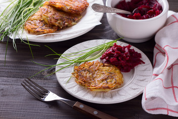 Potato fritters, beet salad, green onions on a wooden surface