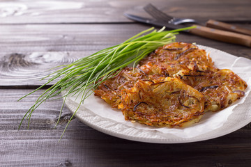 Potato fritters, green onions on a wooden surface