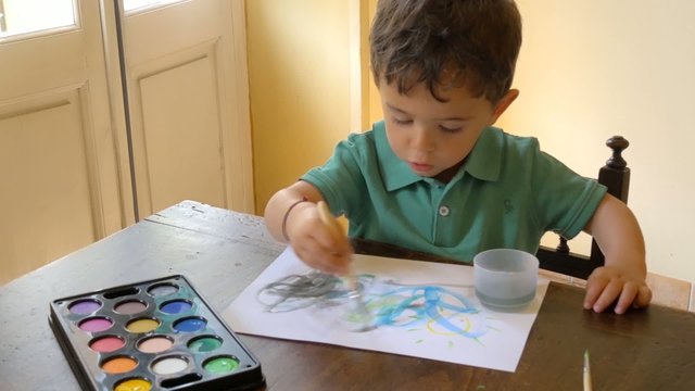 portrait of little boy painting with watercolors