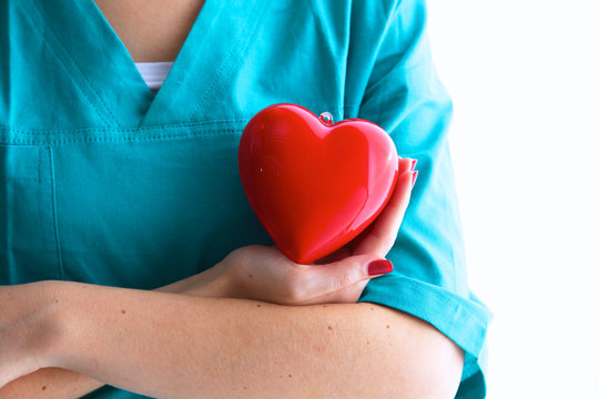 Female Doctor With Stethoscope Holding Heart Over White