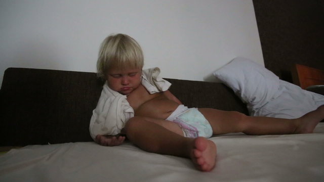blonde little girl sleeps and rolls sitting on sofa	