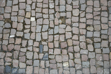 Pavement of grey and pinkish cobblestones as background.
