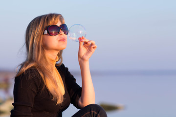 Young girl in sunglasses blowing soap bubbles