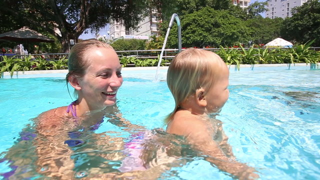 little girl bathes with mother in city pool	