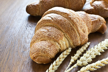 Fresh croissants on dark wooden table for breakfast.
