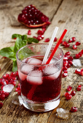 Fresh red juice cocktail with pomegranate seeds, mint and ice, s