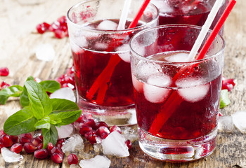 Fresh red juice cocktail with pomegranate seeds, mint and ice, s