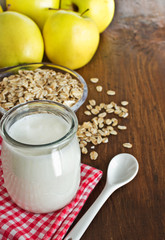 Homemade yogurt with apples and oatmeal on wooden table.
