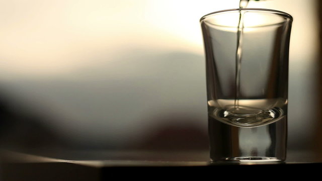 Pouring of gold color alcohol drink with sunset background