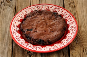 Chocolate pie in red plate on wooden background