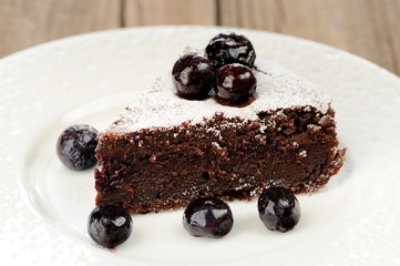 Piece of chocolate pie with whole blueberries and icing sugar in