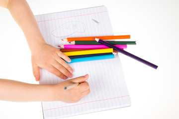 Child drawing in sketchbook  with color pencils.